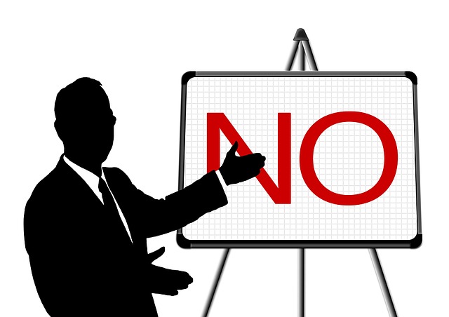 A drawing of a man in a suit pointing to the word "NO" on a blackboard. (A Serbian teacher's reaction when you say, "Putovam".)