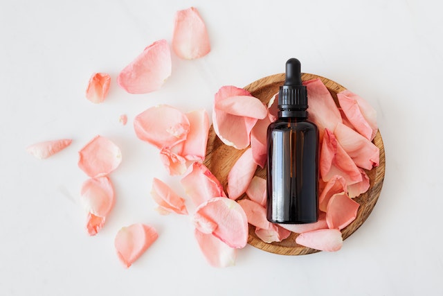 A bottle of medicine in a wooden stand with rose petals