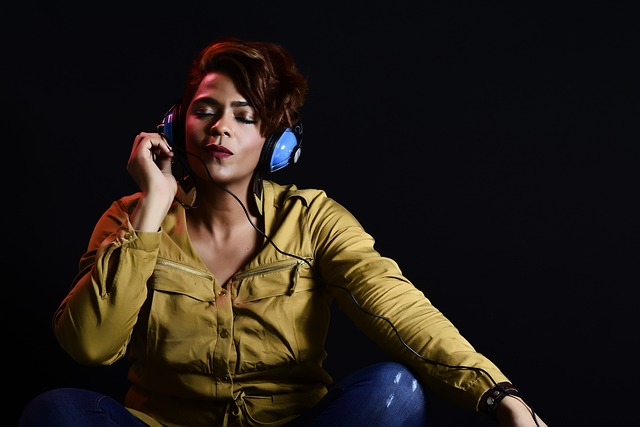 A woman in a yellow jacket and blue headphones enjoying music with her eyes closed.(Have fun and learn Serbian with music!)
