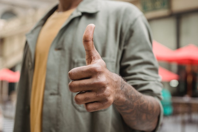 Man in a yellow shirt and a green jacket showing a thumb gesture that means "like".(Serbian learning tips: learn to say what you like in Serbian!)