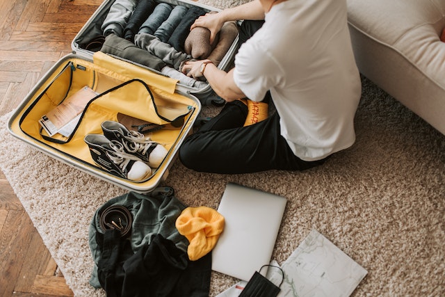 A man sitting on the carpet and packing his stuff in a yellow-grey suitcase.
(A great way to learn the language is to make a packing list in Serbian!)