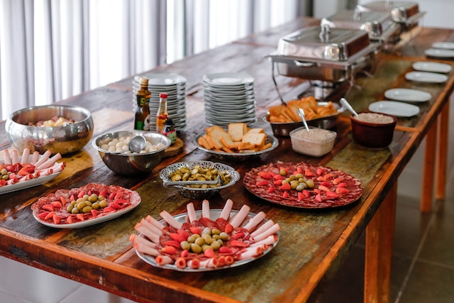 A wooden table with a buffet. There are salami, pastrami, olives, bread, eggs, and various spreads.
(Would you opt for a buffet or a continental breakfast in a Serbian hotel?)